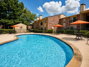 Irving townhouse for rent - A swimming pool surrounded by a patio with chairs and umbrellas.