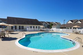 Dover apartment for rent - A large outdoor swimming pool with a white fence surrounding it.