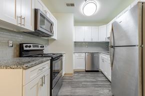 Dover apartment for rent - A kitchen with a black stove top oven and a black microwave.