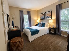 Columbus townhouse for rent - A bedroom with a large bed and a wicker stool.
