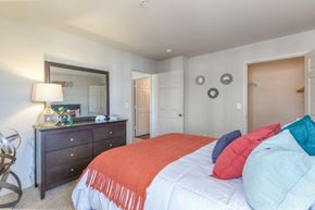 Owasso apartment for rent - A bedroom with a bed, dresser, and mirror.