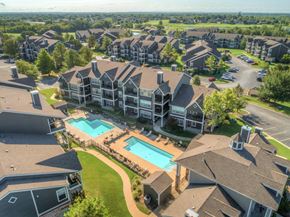 Owasso apartment for rent - A large residential complex with a swimming pool in the foreground.