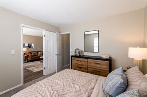 Dayton apartment for rent - A bedroom with a large bed, a dresser with a mirror, and a lamp.