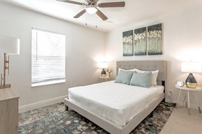 West Palm Beach apartment for rent - A bedroom with a large bed, a ceiling fan, and a window with blinds.