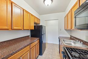 Reading apartment for rent - a kitchen with wooden cabinets and a black refrigerator