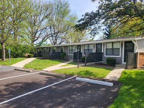 Muncie townhouse for rent - A parking lot in front of a building with trees in the background.