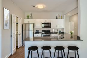Fort Worth townhouse for rent - A modern kitchen with white cabinets and black stools.