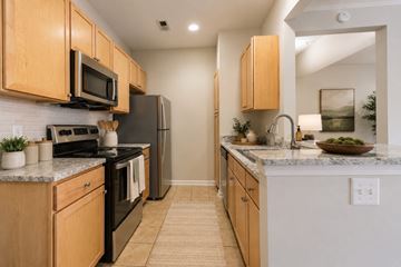 Charlotte townhouse for rent - A kitchen with wooden cabinets and black appliances.