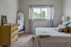 Wyoming apartment for rent - A bedroom with a bed, nightstand, and window with curtains.
