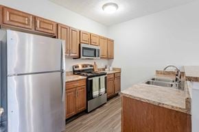Louisville apartment for rent - A kitchen with a refrigerator, microwave, oven, and sink.