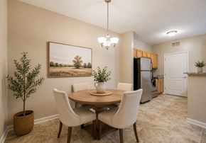 Mebane apartment for rent - A dining room with a round table and chairs, a potted plant, and a painting on the wall.
