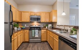 Mebane apartment for rent - A kitchen with wooden cabinets and a stainless steel refrigerator.