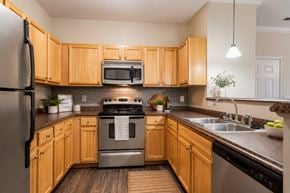 Mebane apartment for rent - A kitchen with wooden cabinets and a stainless steel refrigerator.
