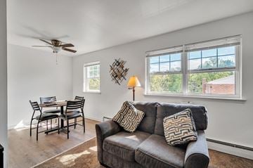Carlisle apartment for rent - A living room with a grey couch, a dining table with chairs, a ceiling fan, and a window with a view of the outdoors.