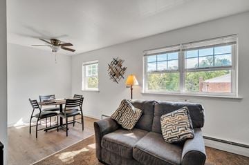 Carlisle apartment for rent - A living room with a grey couch, a dining table with chairs, a ceiling fan, and a window with a view of the outdoors.