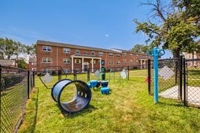 Carlisle apartment for rent - A playground with a blue slide and a black fence in front of a brick building.
