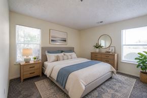 Fayetteville apartment for rent - A bedroom with a large bed, a nightstand with a lamp, and a plant on the windowsill.