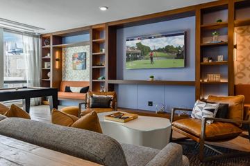 Chicago apartment for rent - A living room with a grey sofa, a coffee table, and a television playing a golf game.