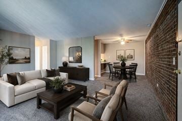 Kettering apartment for rent - A living room with a white couch, a wooden coffee table, and a dining table with chairs.