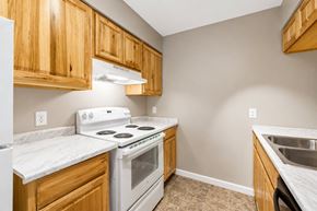 Kettering apartment for rent - A kitchen with wooden cabinets and a white stove top oven.