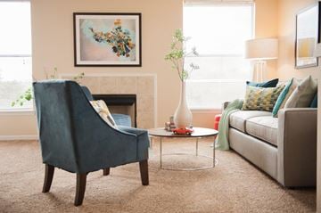Memphis apartment for rent - A living room with a blue chair, a white couch, and a painting on the wall.