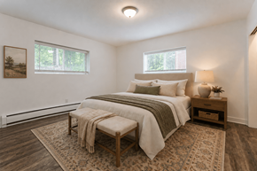 Webster apartment for rent - A bedroom with a large bed and a bench in front of it.