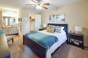 Louisville apartment for rent - A bedroom with a bed, a ceiling fan, and a nightstand.