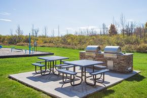 Reading apartment for rent - Picnic tables and grills are set up on a concrete slab in a grassy area.