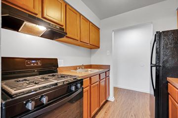 Carlisle apartment for rent - A kitchen with a black refrigerator, wooden cabinets, and a black stove top oven.