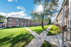 Carlisle apartment for rent - a large brick building with a lawn and trees in front of it