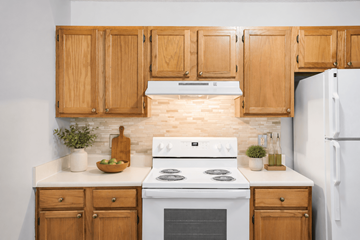High Point apartment for rent - A kitchen with wooden cabinets and a white stove top oven.