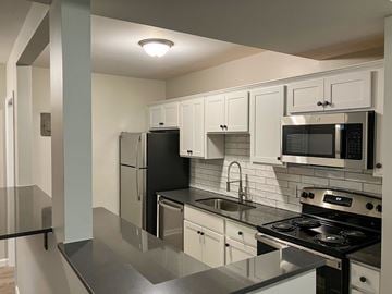 Webster apartment for rent - A kitchen with black appliances and white cabinets.