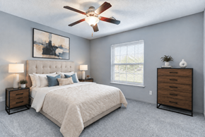 Schaumburg apartment for rent - A bedroom with a large bed, a ceiling fan, and a window.