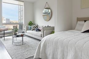Chicago apartment for rent - A bedroom with a large bed and a view of the city.