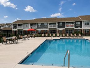 Dayton apartment for rent - A swimming pool in front of a building with a red umbrella.