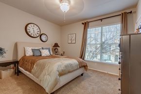 Tulsa apartment for rent - A bedroom with a large bed and two clocks on the wall.
