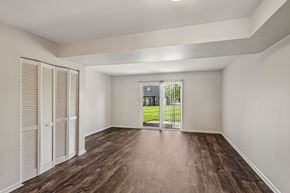 Middletown apartment for rent - A room with wooden floors and white walls, with a view of a green lawn and a building through a glass door.