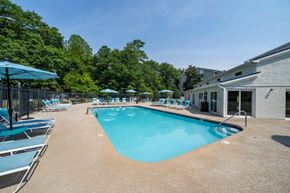 Fayetteville apartment for rent - A large outdoor swimming pool surrounded by lounge chairs and umbrellas.
