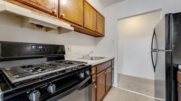 Reading apartment for rent - A black stove top oven sits in a kitchen with wooden cabinets.