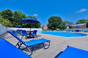 Quakertown apartment for rent - A pool area with blue chairs and umbrellas.