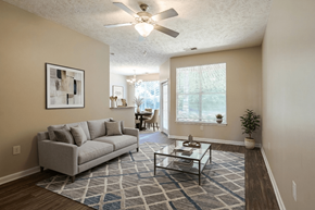 Fayetteville apartment for rent - A living room with a grey couch, a glass coffee table, and a ceiling fan.