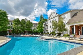 Columbus townhouse for rent - A swimming pool surrounded by lounge chairs and trees in front of apartment buildings.