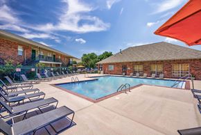Oklahoma City apartment for rent - A pool surrounded by lounge chairs and umbrellas.