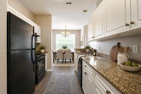 Fayetteville apartment for rent - A black refrigerator is on the left in a kitchen with granite countertops and white cabinets.