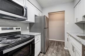 Allison Park apartment for rent - A kitchen with a black stove top oven and a stainless steel refrigerator.