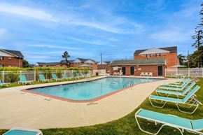 Allentown apartment for rent - A large outdoor swimming pool surrounded by sun loungers and a building in the background.