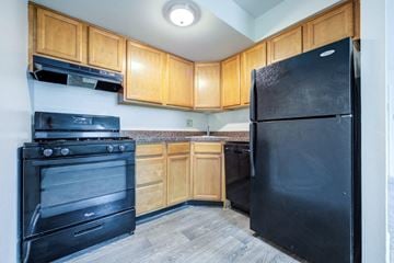 Allentown apartment for rent - A black refrigerator stands in a kitchen with wooden cabinets and a black stove.