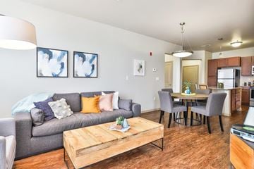 Saint Charles apartment for rent - A living room with a grey couch, a wooden coffee table, and a dining table with chairs.