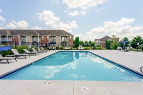 Beavercreek apartment for rent - A large swimming pool with lounge chairs and apartment buildings in the background.