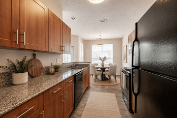 Fayetteville apartment for rent - A kitchen with a black refrigerator and wooden cabinets.